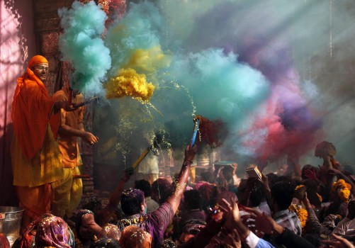 Hindu priests throws coloured powder at the devotees during Holi celebrations at Bankey Bihari temple in Vrindavan